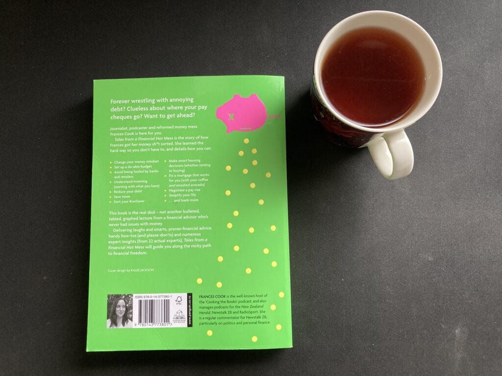 Back cover of Tales From A Financial Hot Mess with a cup of tea next to it
