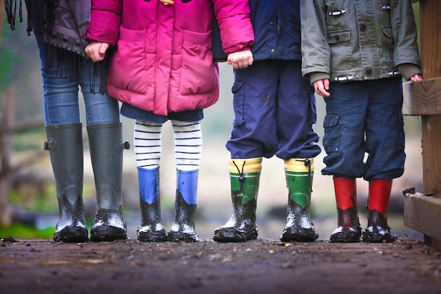 four children from neck down in outdoor clothing wearing gumboots