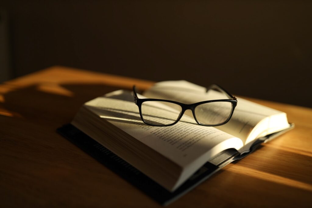 an open book with glasses on top of it. Financial literacy needs to be learnt