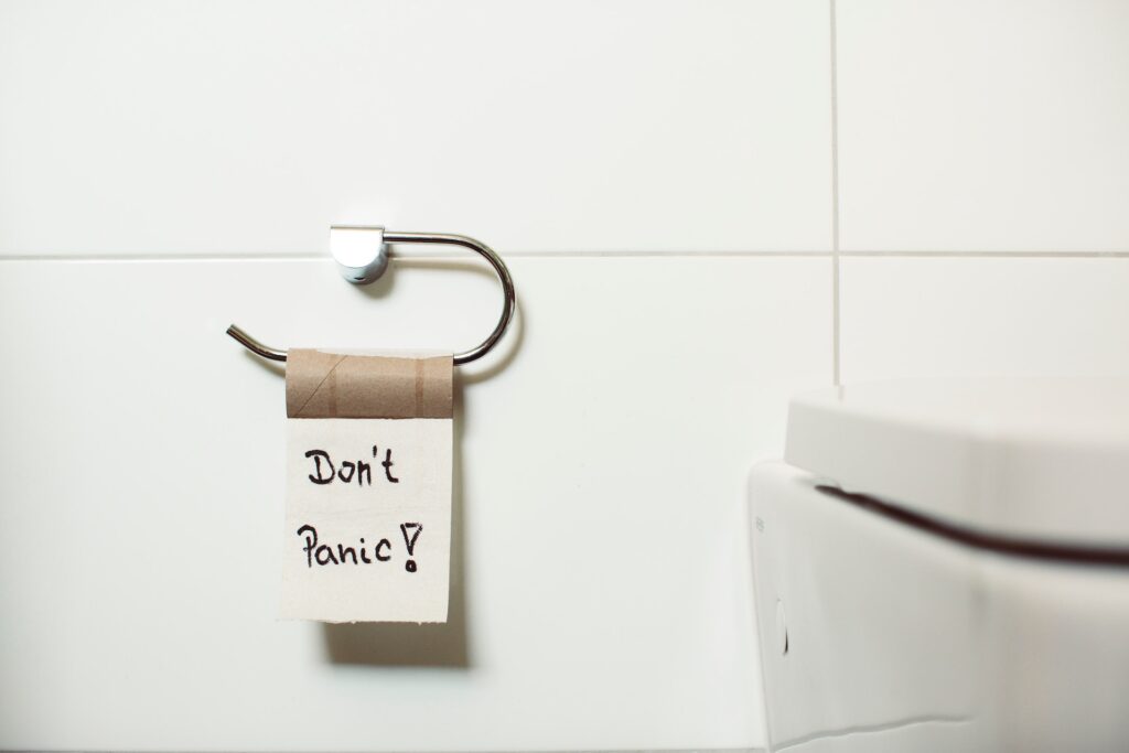 Empty toilet paper roll that has text written on it, it says don't panic. Negative money mindset can make your financial stress worse